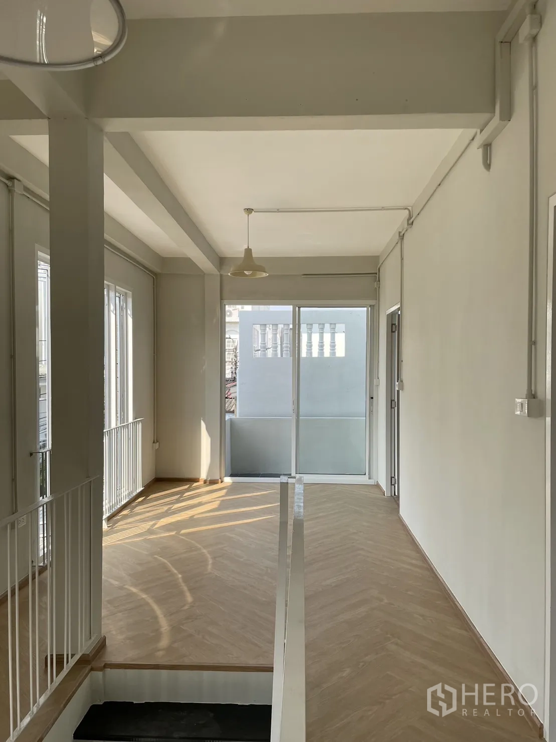 Detached House for rent or sale in Din Daeng, Bangkok - Upper hallway with long herringbone floor and balcony-facing glass doors.