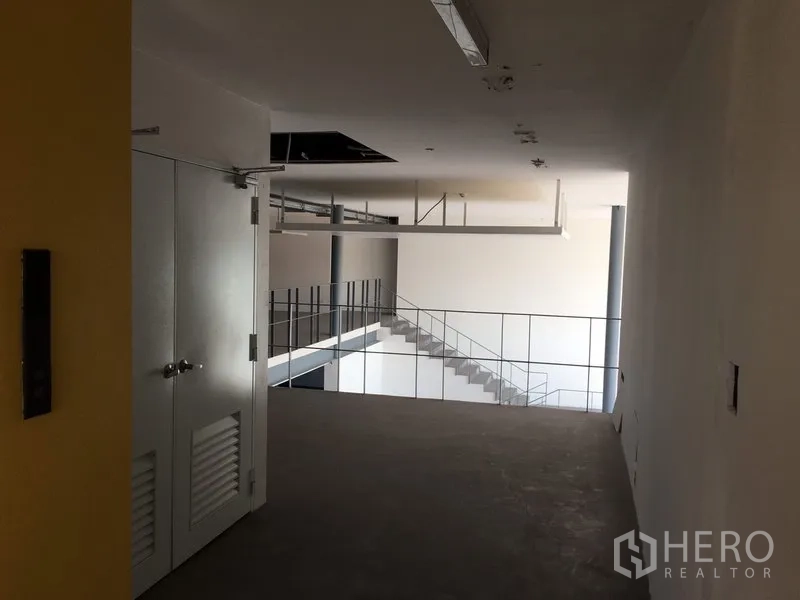 Warehouse for rent in Saphan Sung, Bangkok - Upper floor corridor overlooking central atrium with staircase and railing.