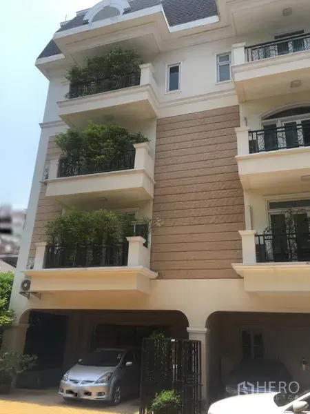 Townhouse for sale in Huai Khwang, Bangkok - Four-storey townhouse facade with balconies, greenery and covered parking in Huai Khwang.