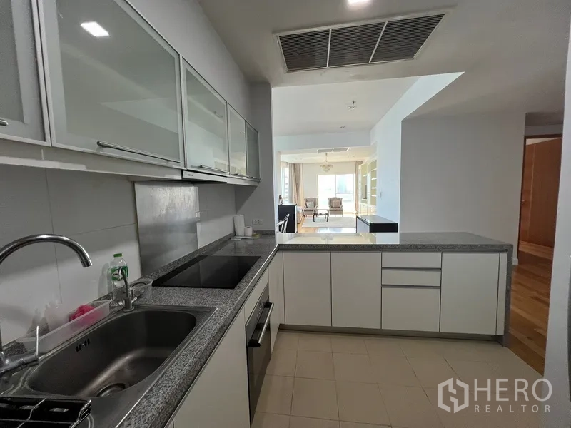 Condominium for rent in Khlong Toei, Bangkok - Open-plan kitchen with breakfast counter overlooking the living area.