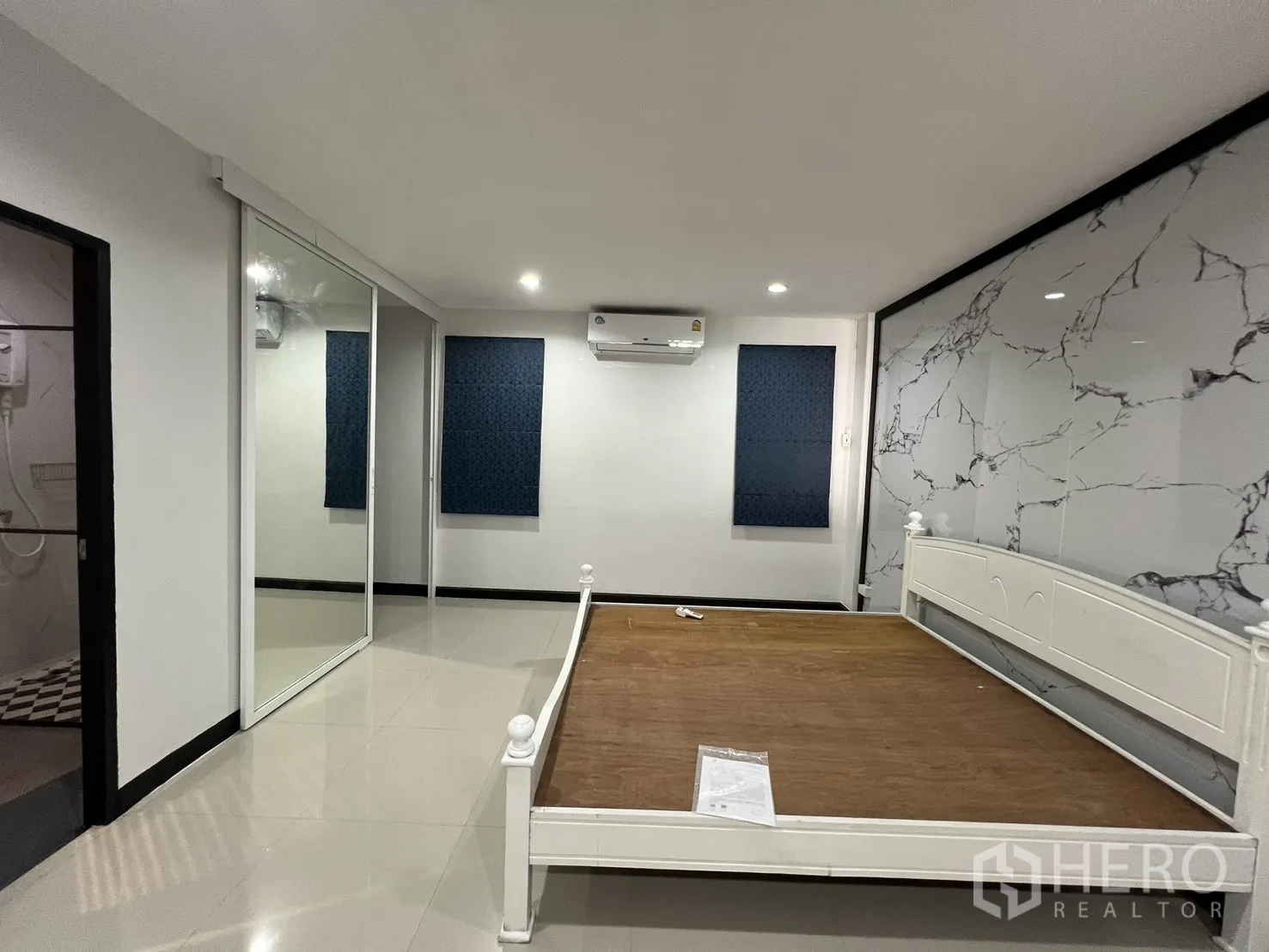 Townhouse for rent in Watthana, Bangkok - Bedroom with white bed frame, marble accent wall, air conditioner and mirrored closet.
