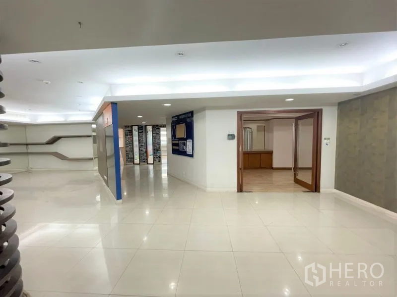 Office Space for rent in Chatuchak, Bangkok - Building lobby with bright tiled floors, recessed lighting, and a wood-framed entry to a meeting area.