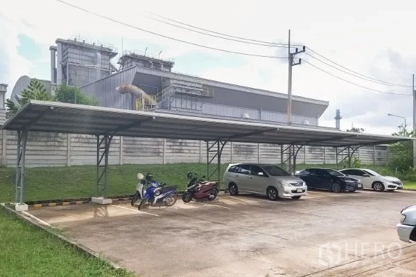 Factory for sale in Rayong - Covered car park with marked bays for cars and motorcycles beside the perimeter wall.
