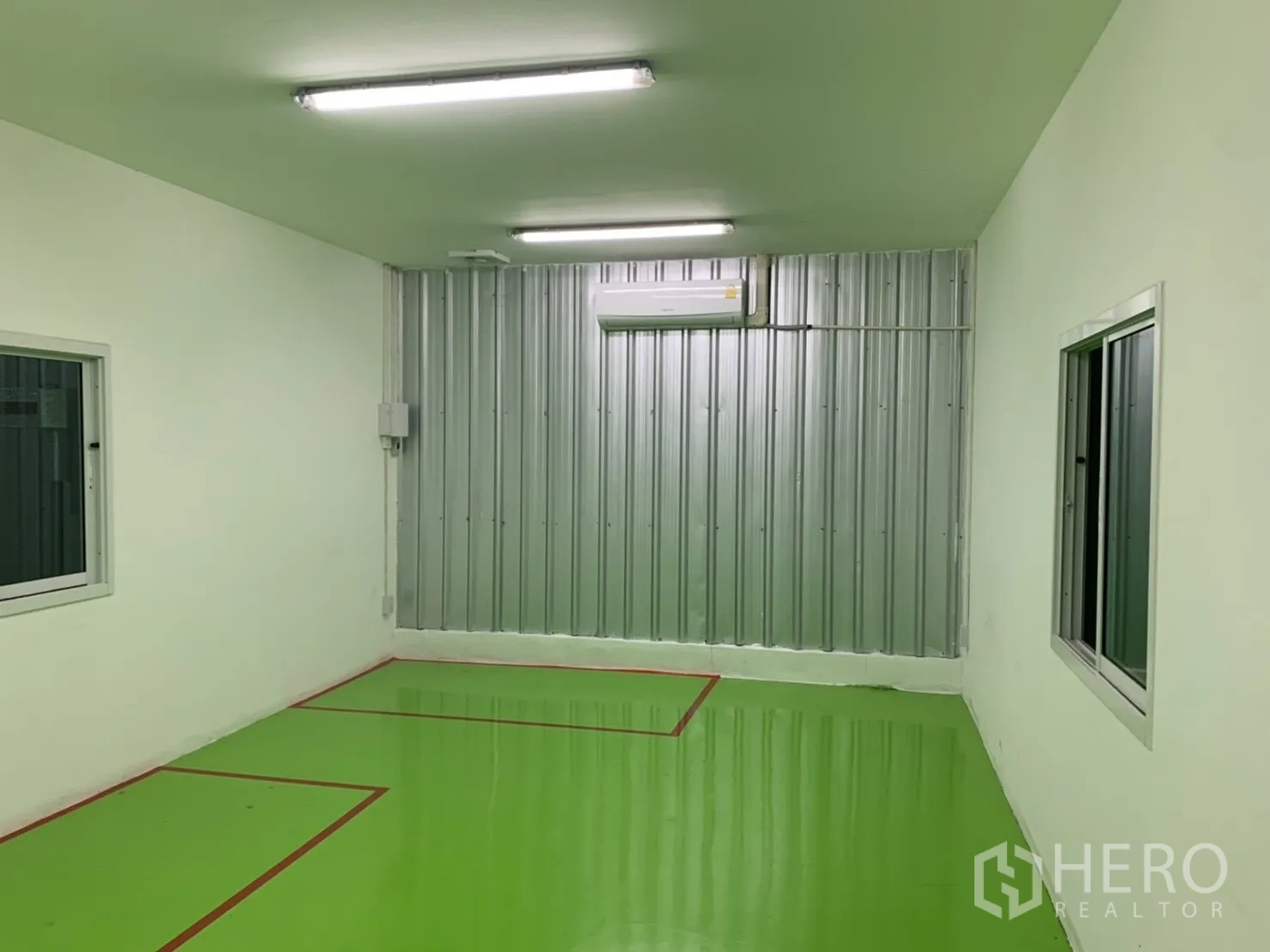 Factory for rent in Khlong Luang, Pathum Thani - Smaller processing room with green epoxy floor, metal wall panels, and red floor markings.
