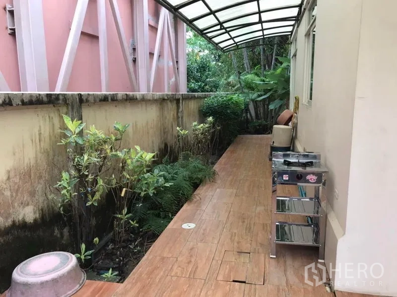 Detached House for rent in Bang Khen, Bangkok - Covered side yard with tiled walkway, outdoor counter and planted shrubs along the wall.