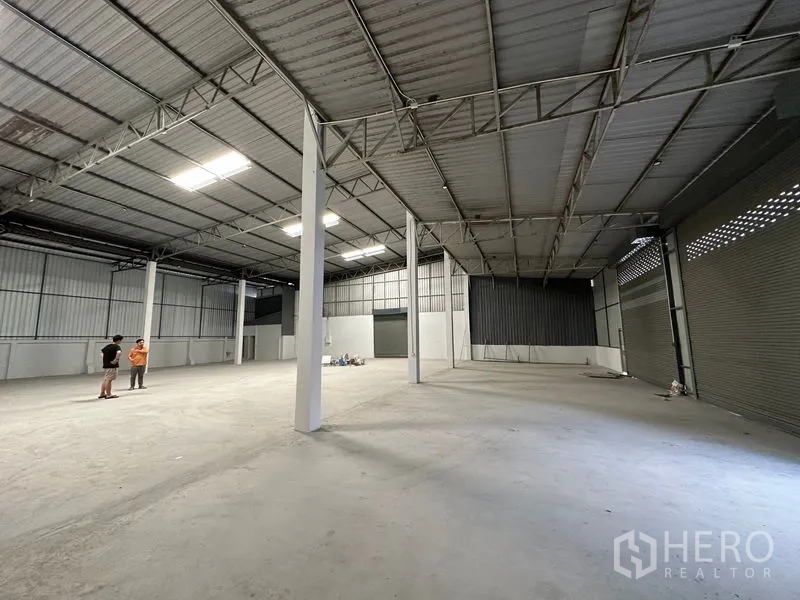 Warehouse for rent in Khlong Luang, Pathum Thani - Warehouse interior facing multiple roller doors and ventilation blocks, ready for storage or operations.