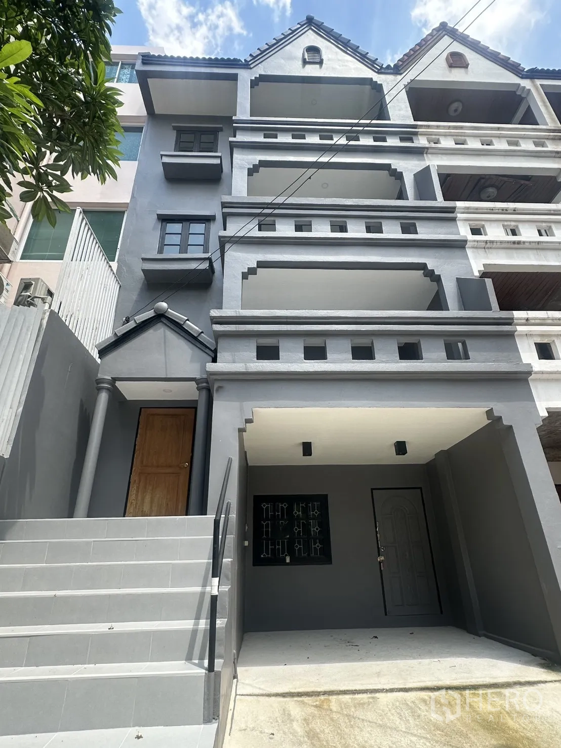 联排别墅 for rent in Watthana, Bangkok - 灰色四层联排别墅外立面，带多层阳台、前阶入口和遮蔽车位