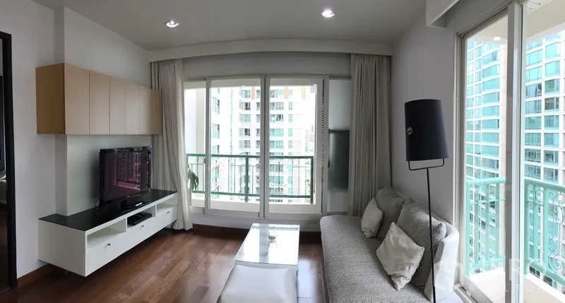 Condominium for rent in Pathum Wan, Bangkok - Panoramic view of the living room with sofa, coffee table and balcony overlooking city buildings.