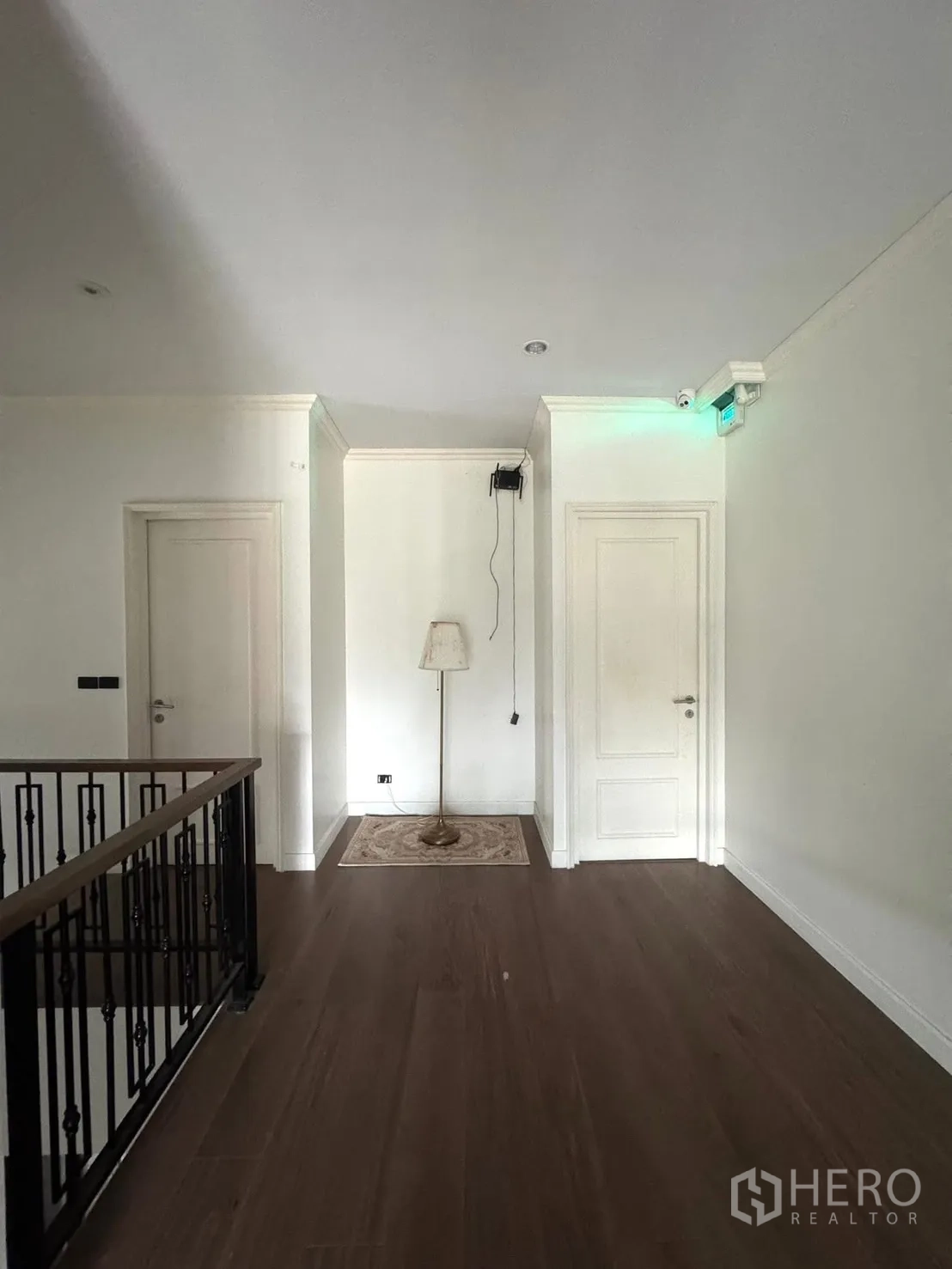 Detached House for sale in Mueang Pathum Thani, Pathum Thani - Upstairs hallway with wooden floors, white doors and iron balustrade.