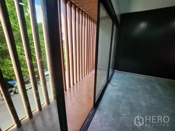Warehouse for rent in Lam Luk Ka, Pathum Thani - Balcony with vertical wooden louvers and sliding glass doors overlooking greenery.