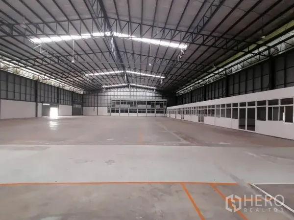 Warehouse for rent in Lat Krabang, Bangkok - Spacious column-free warehouse interior with high steel truss roof, skylights and glass-partitioned office rooms.