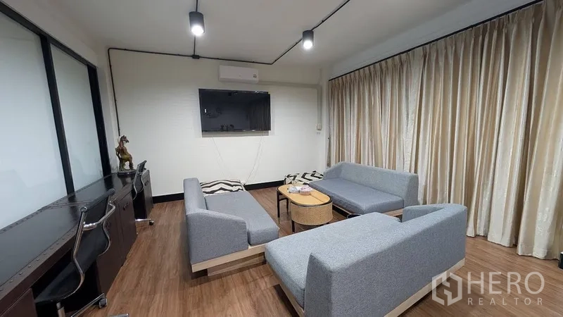 Home Office for rent or sale in Phra Khanong, Bangkok - Work lounge with desk chairs, wall-mounted TV and gray sofas.