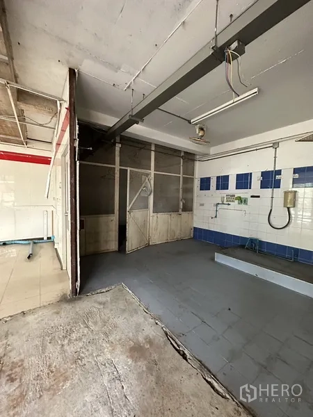 Retail Space for rent in Watthana, Bangkok - Rear service area with tiled walls, utility lines and partitioned storage in a vacant retail shop, Watthana, Bangkok.