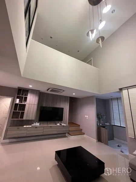Townhouse for sale in Saphan Sung, Bangkok - View up to mezzanine from living room showing hanging light fixtures and open void.