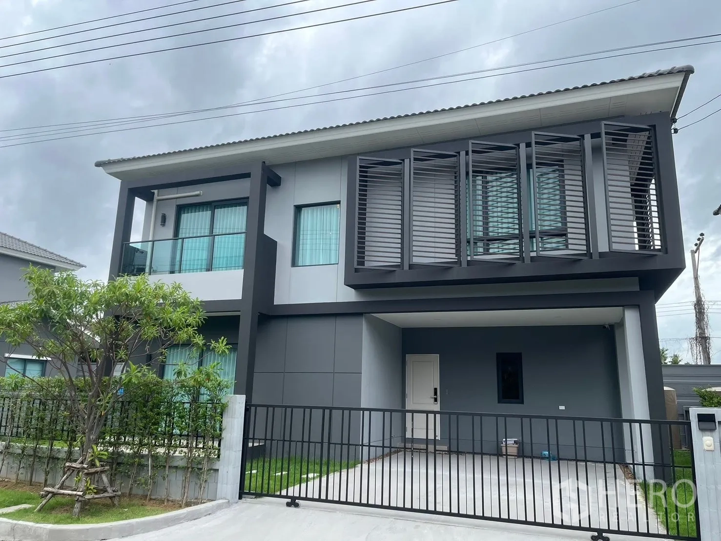 Detached House for rent in Bang Phli, Samut Prakan - Modern two-storey detached house with balcony, sunshade screens and a gated carport.