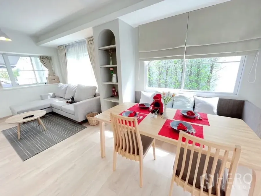 Townhouse for rent in Prawet, Bangkok - Bright open-plan living and dining area with L-shaped sofa, light wood floors and large windows in a Prawet Bangkok townhouse.