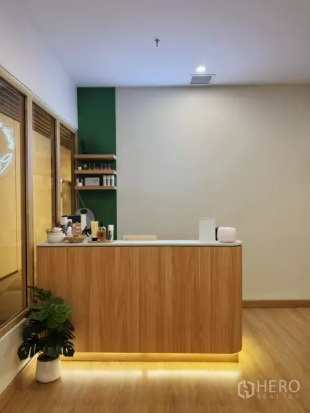 Retail Space for rent - Minimalist reception counter in light wood with shelving and warm underlighting inside the salon.