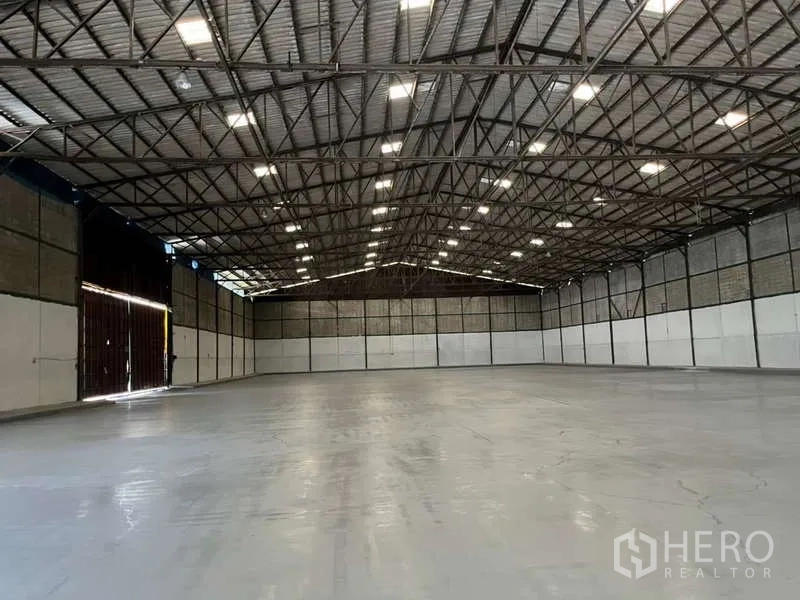 Factory for rent in Bang Pakong, Chachoengsao - Expansive factory interior with high steel truss roof, polished concrete floor, and bright ceiling lights.