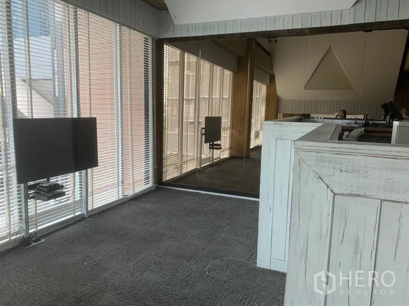 Retail Space for rent in Watthana, Bangkok - Loft-style retail interior with floor-to-ceiling windows, blinds, mirrored wall and a rustic counter.