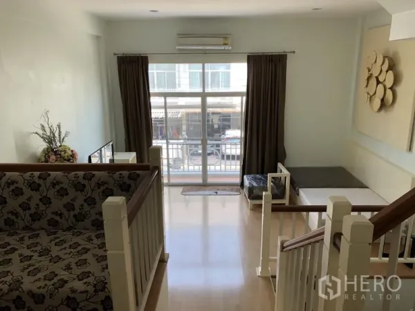 Townhouse for rent in Prawet, Bangkok - Upper lounge with wood flooring, large window and balcony access.