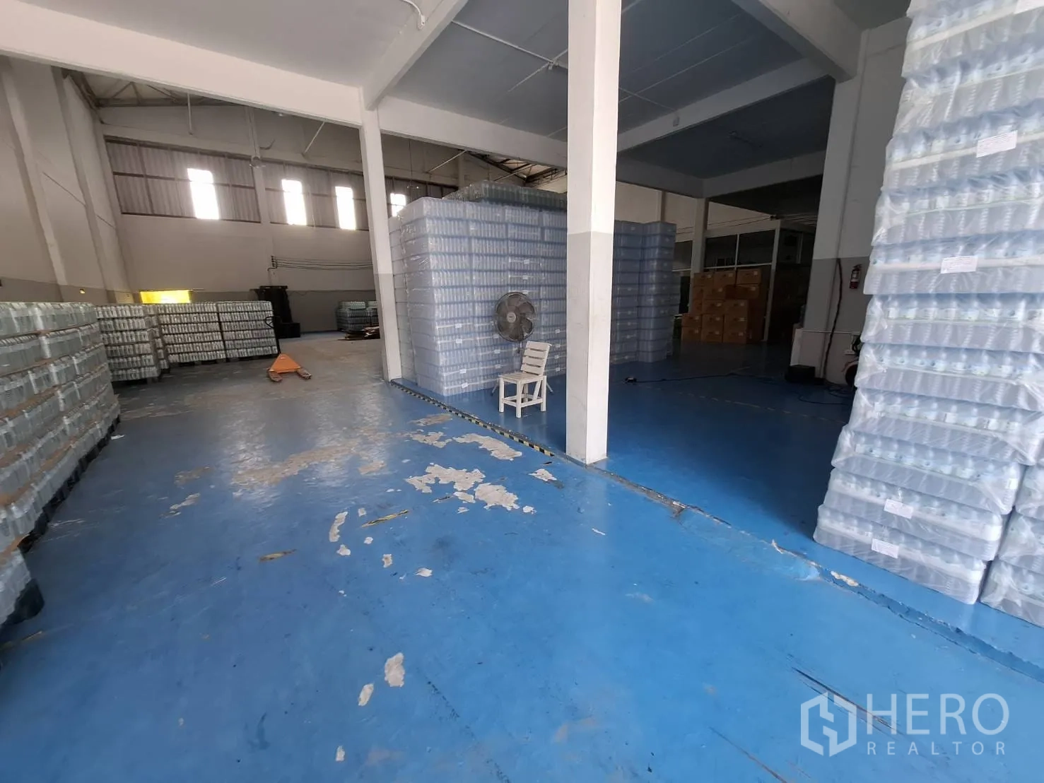 Factory for rent in Bang Phli, Samut Prakan - Warehouse aisle with stacked bottled products on pallets and clear forklift space.