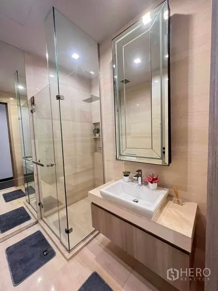 Condominium for rent or sale in Watthana, Bangkok - Contemporary bathroom featuring a glass-enclosed shower, large framed mirror and floating vanity.