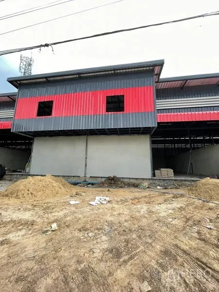 Warehouse for rent in Pathum Thani - Front block with red and gray cladding above solid walls during construction.