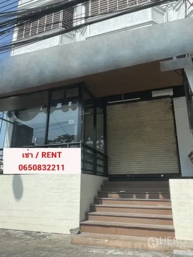 Retail Space for rent in Bang Na, Bangkok - Street-front retail unit in Bang Na with glass façade, roll-up shutter, raised entrance steps, and a ‘For Rent’ sign.