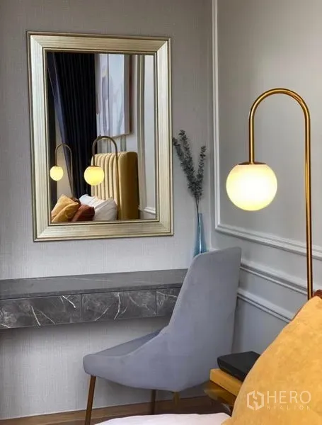 Condominium for rent - Bedroom vanity corner featuring a marble floating desk, framed mirror and globe floor lamp.