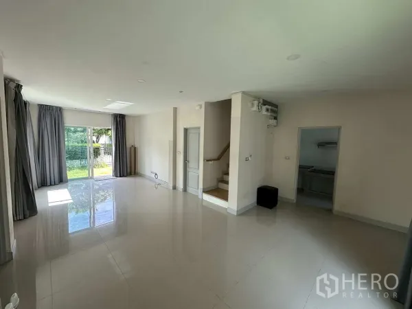 Detached House for rent in Khlong Luang, Pathum Thani - Bright open-plan living area with glossy tile floors and staircase to upper level.