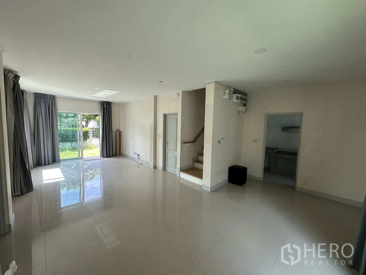 Detached House for rent in Khlong Luang, Pathum Thani - Bright open-plan living area with glossy tile floors and staircase to upper level.