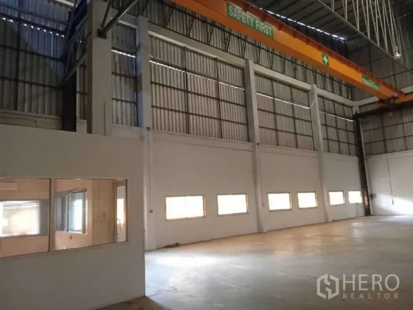 Factory for rent in Mueang Samut Prakan, Samut Prakan - Factory bay showing safety-marked overhead crane above and adjacent internal office windows.