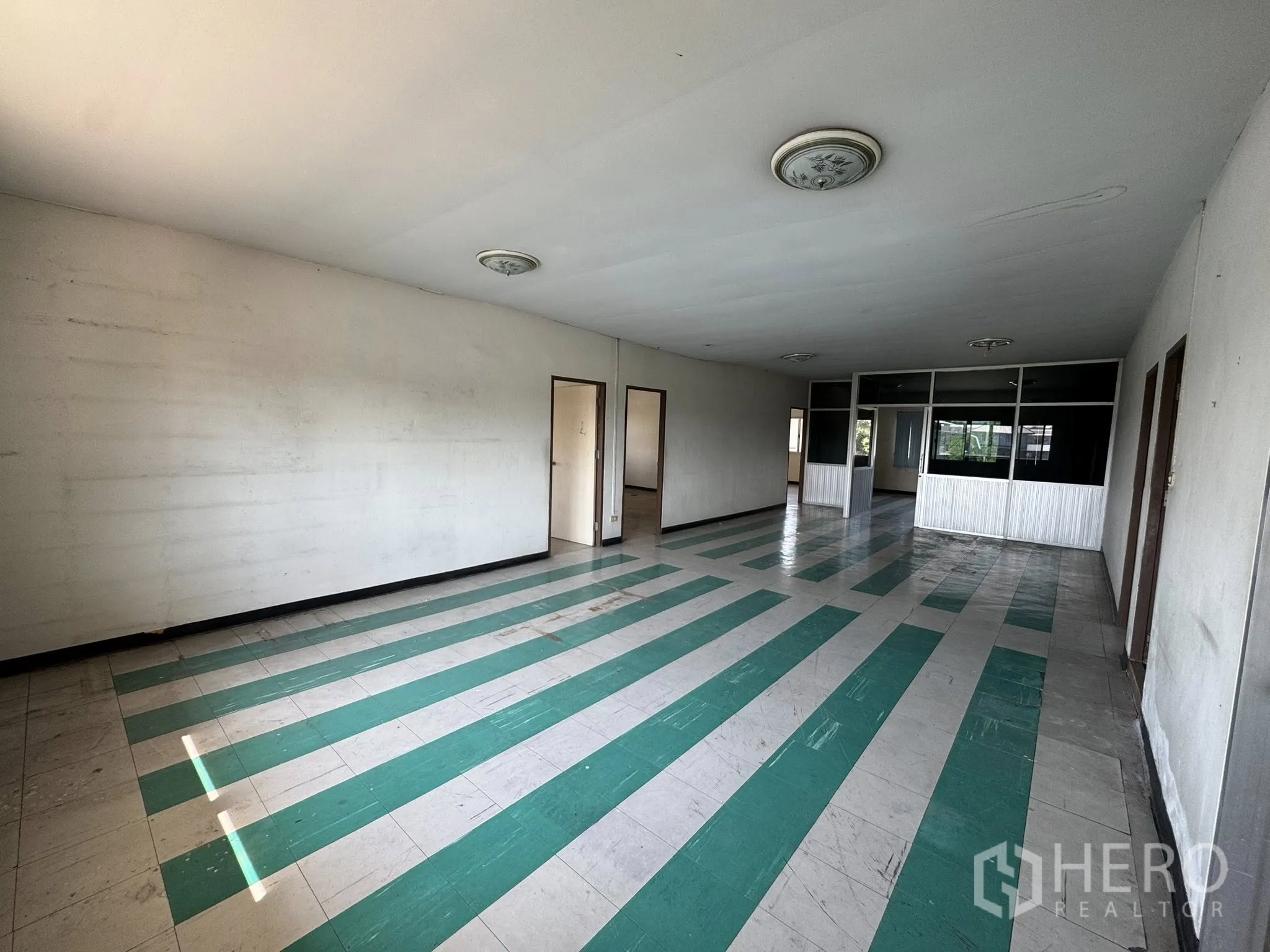Warehouse for rent in Mueang Samut Sakhon, Samut Sakhon - Long open-plan office area with green-and-white striped flooring and glass partitions.