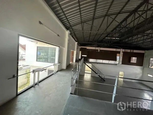 Warehouse for rent in Phra Khanong, Bangkok - Mezzanine walkway overlooking a high-ceiling warehouse with large windows and steel truss roof.