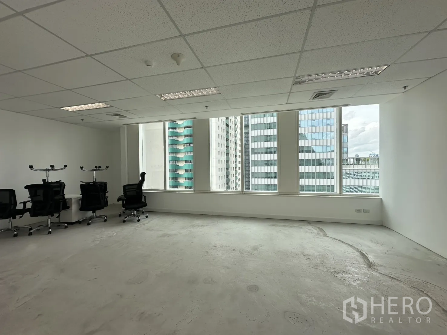 Office Space for rent in Watthana, Bangkok - Bright open-plan office with large windows, white walls, and task chairs facing city towers.