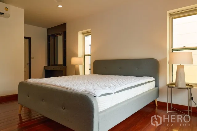 Detached House for rent in Watthana, Bangkok - Bedroom with vanity corner, bedside lamps and wood floors.