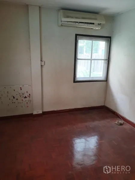 Detached House for rent or sale in Watthana, Bangkok - Unfurnished room with wall-mounted air conditioner, single window and polished parquet floor.