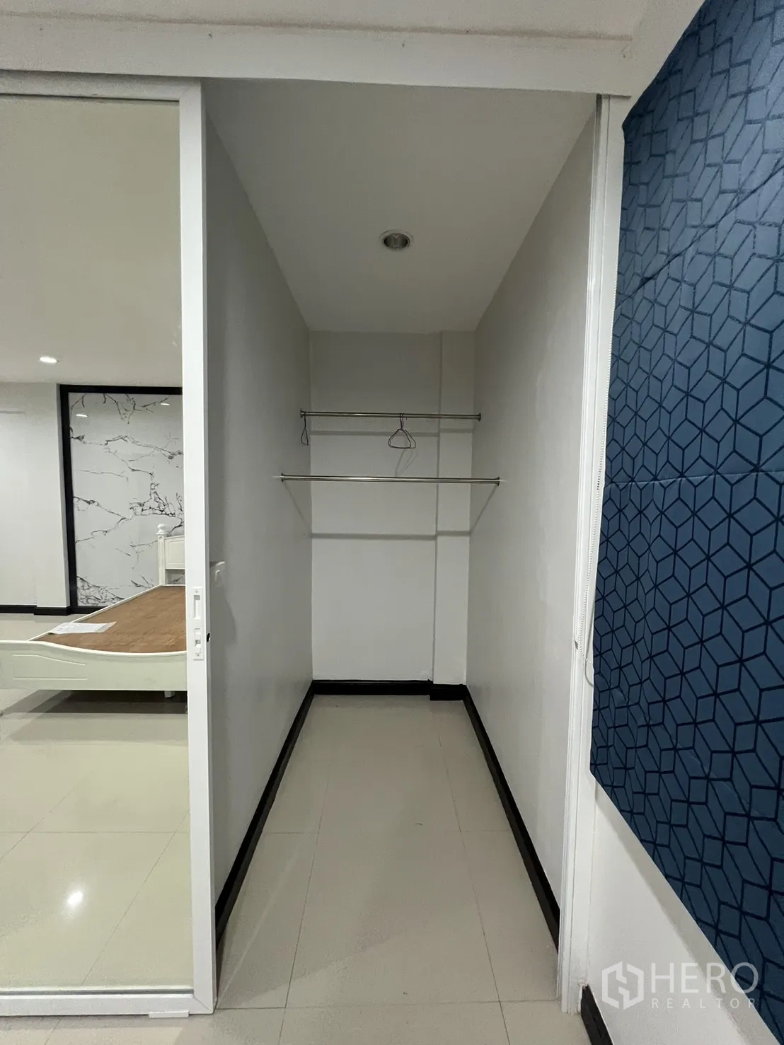 Townhouse for rent in Watthana, Bangkok - Walk-in closet nook with sliding door and hanging rails.