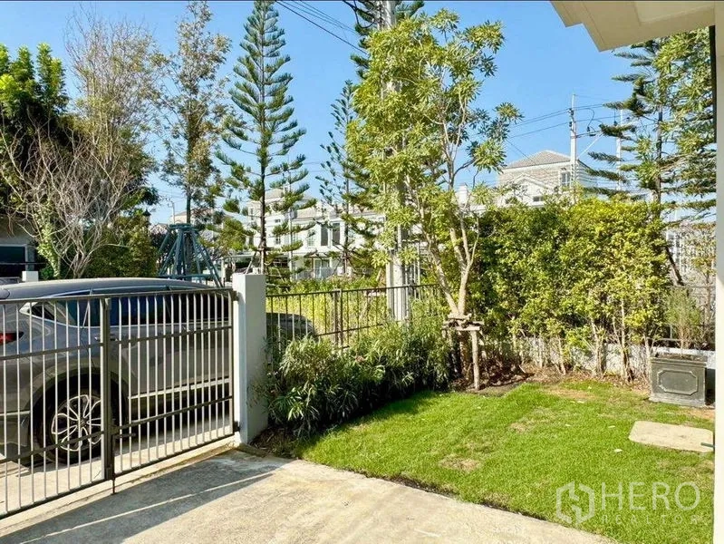 Townhouse for rent or sale in Prawet, Bangkok - Gated driveway with lawn and trees providing private outdoor space.