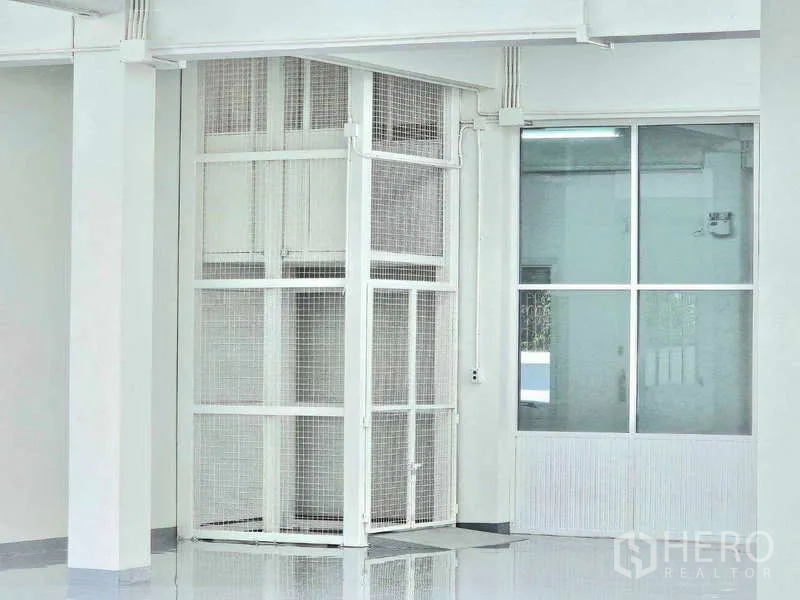 Warehouse for rent in Mueang Samut Prakan, Samut Prakan - Caged goods lift inside the warehouse for materials handling.