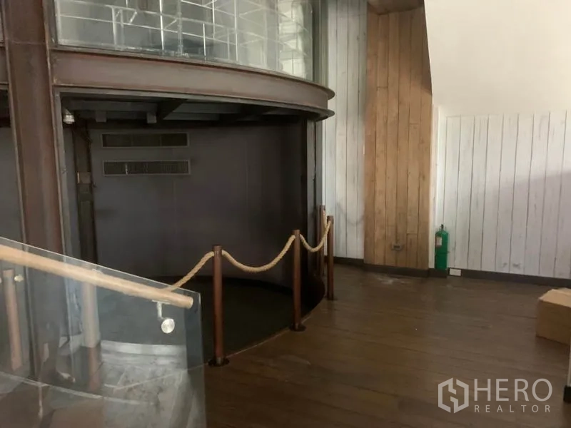 Retail Space for rent in Watthana, Bangkok - Ground-level area with wood flooring, a curved feature wall, rope divider and glass railing.