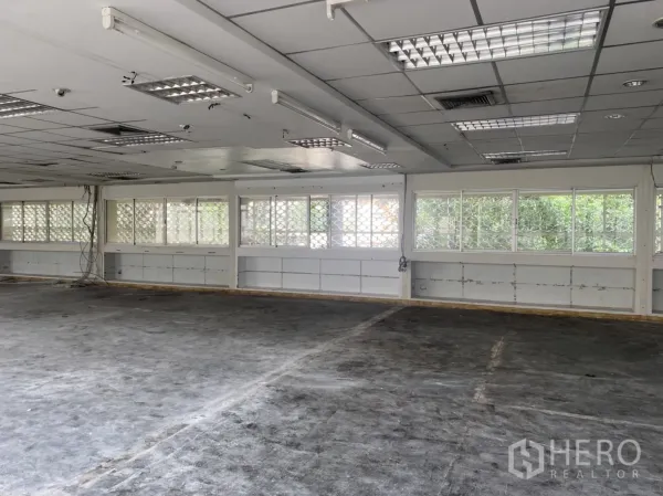 Office Space for rent in Khlong Toei, Bangkok - Rear office zone showing grid windows with privacy blocks, fluorescent light panels and open plan.