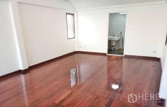 Home Office for rent in Chatuchak, Bangkok - Spacious bedroom with glossy wooden floors and an ensuite bathroom.