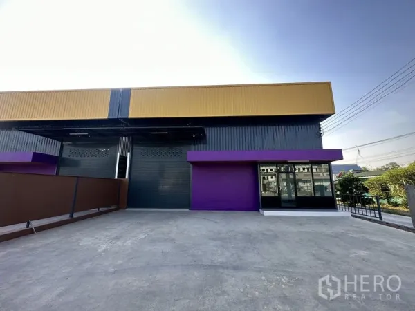 Warehouse for rent in Lam Luk Ka, Pathum Thani - Driveway and loading yard facing the warehouse with a glass-front office on the right.