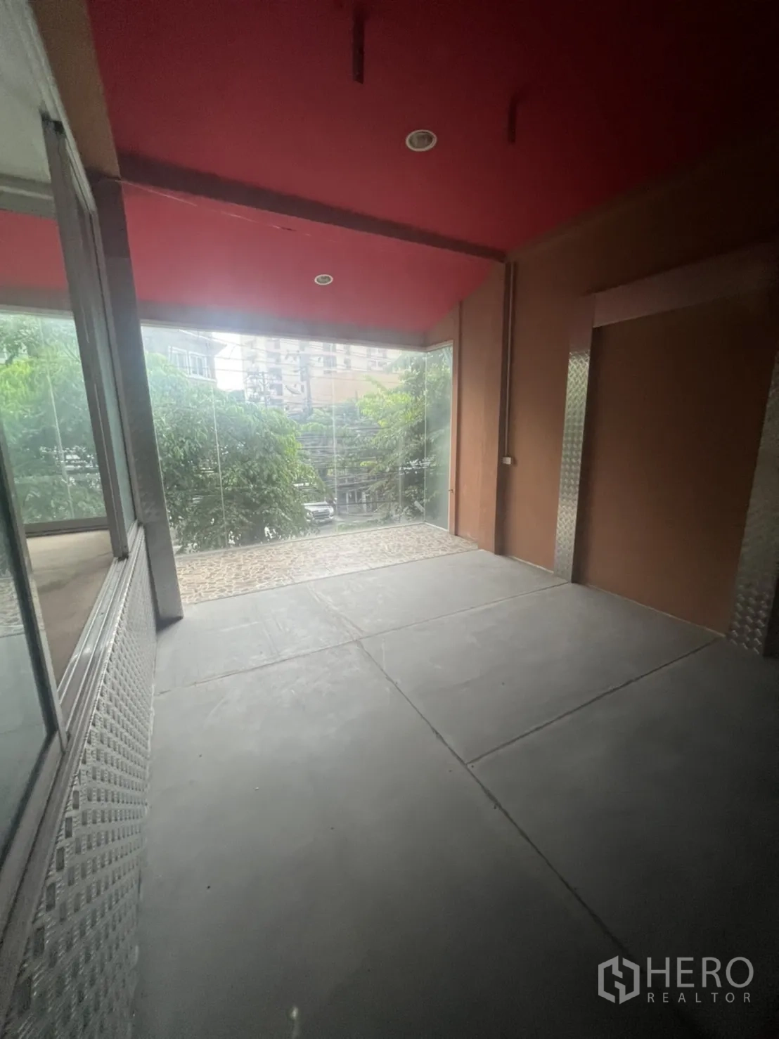Shophouse for rent in Watthana, Bangkok - Bright room with street-view glazing, red ceiling and gray flooring.
