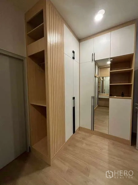 Detached House for rent in Mueang Nonthaburi, Nonthaburi - Built-in corner wardrobe with wood slat accents and mirrored cabinet in a dressing area.