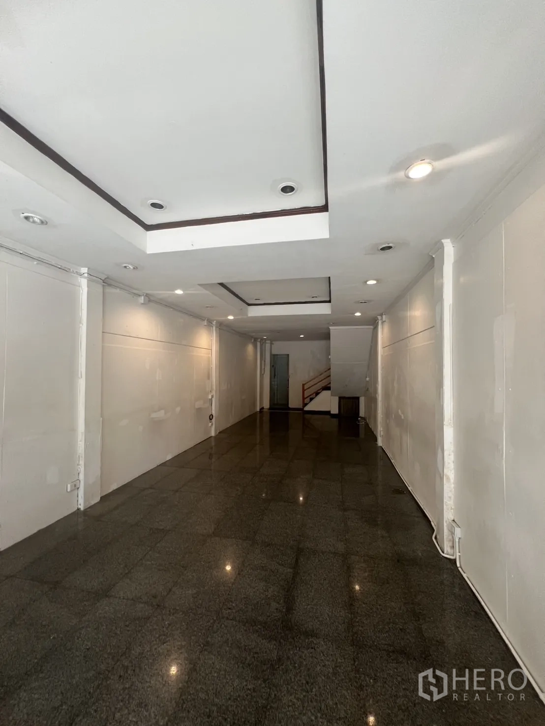 店屋 出租在Khlong Toei, Bangkok - 一层开放式营业空间，吊顶射灯与亮面石材地面。