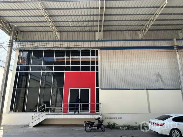 Factory for rent in Bang Phli, Samut Prakan - Glass-fronted factory entrance with red feature panel and raised steps beneath a large metal canopy.