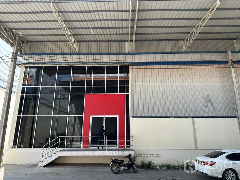 Factory for rent in Bang Phli, Samut Prakan - Glass-fronted factory entrance with red feature panel and raised steps beneath a large metal canopy.