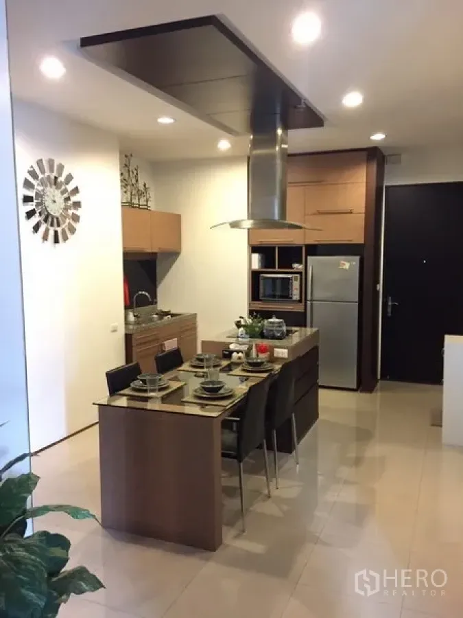 Condominium for rent in Khlong Toei, Bangkok - Modern open kitchen with island cooktop, range hood, wood cabinetry and stainless refrigerator.